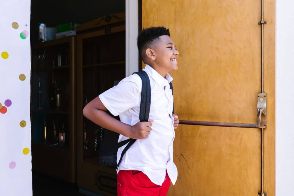 Young students carrying backpacks as they arrive at school
