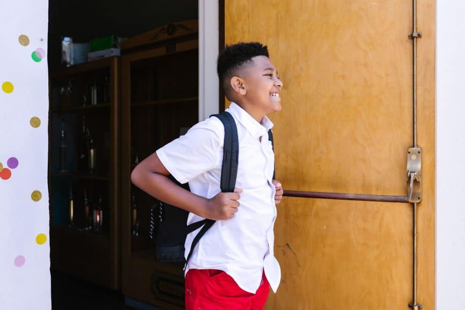 Young students carrying backpacks as they arrive at school