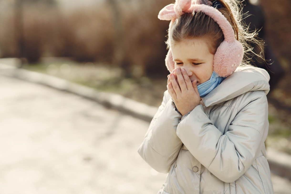 A toddler sneezing while playing on the floor at daycare