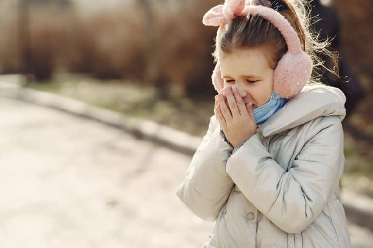 A toddler sneezing while playing on the floor at daycare
