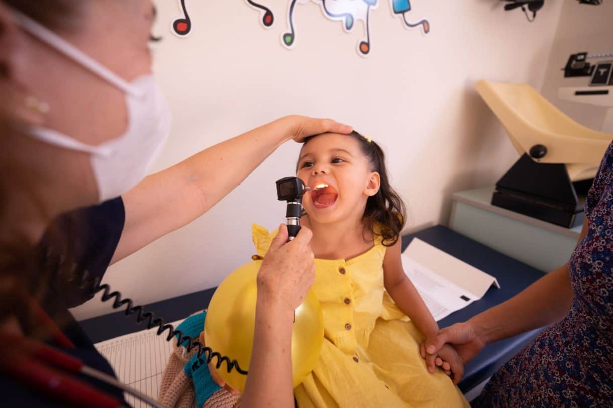 Pediatrician examining a young girl's throat during a clinic visit