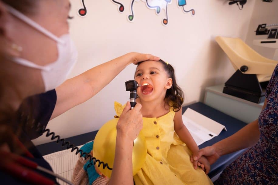 Pediatrician examining a young girl's throat during a clinic visit