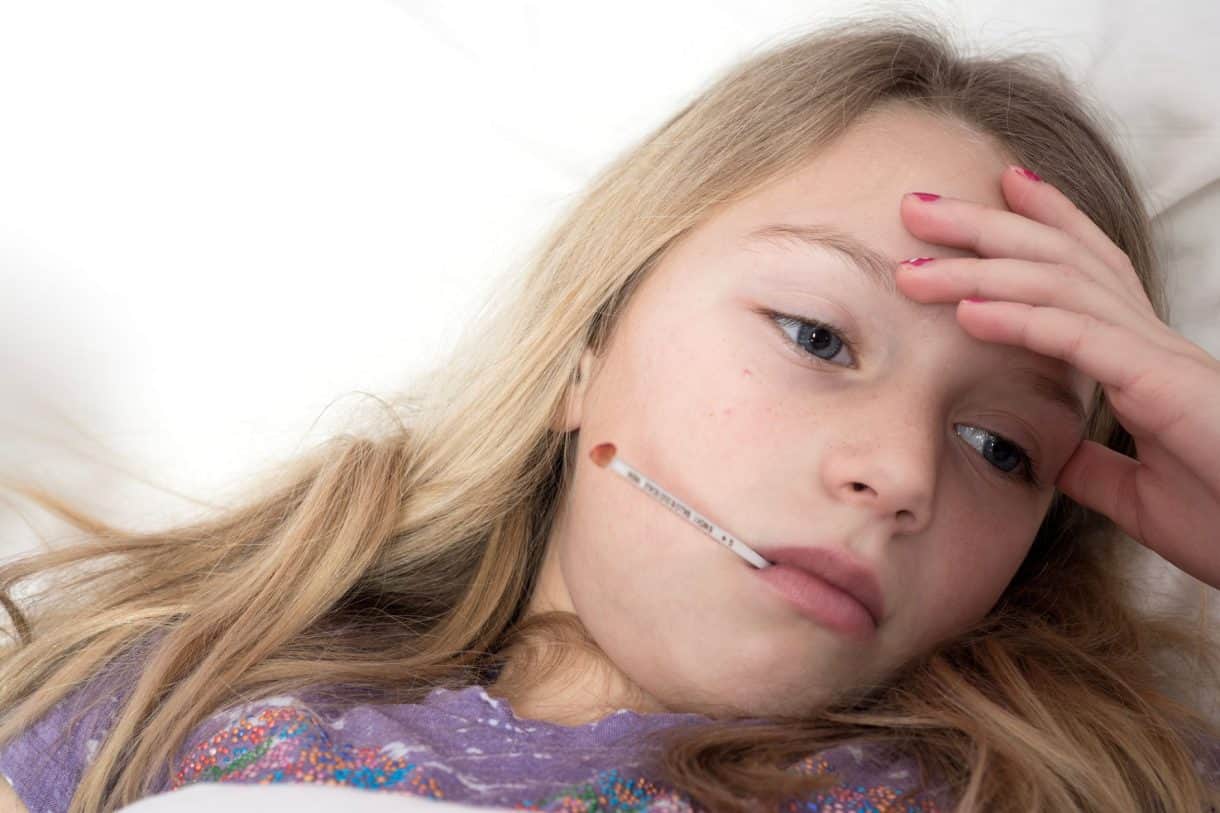 A child resting at home in pajamas on the couch instead of going to school